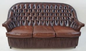A leather three seat sofa with button back and loose seat cushions on casters, maximum 106cm high,