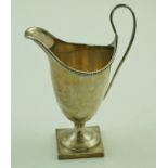 A silver helmet shaped cream jug with a beaded border, a loop handle and a square foot,