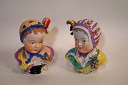 A pair of 19th century Vienna porcelain busts of children each wearing a cap with a feather and bow,