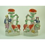 A pair of 19th century Staffordshire pottery spill vases, one modelled with a cow and a milk maid,