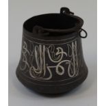 An Islamic cooking pot with swing handle and silvered script band,