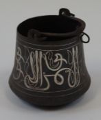 An Islamic cooking pot with swing handle and silvered script band,