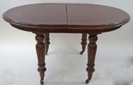 A Victorian style mahogany dining table with turned and reeded legs on brass casters,