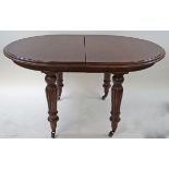 A Victorian style mahogany dining table with turned and reeded legs on brass casters,