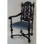 A carved oak Victorian elbow chair with stuff over seat and legs linked by “x” stretchers on flared