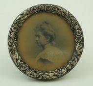 A silver mounted round photograph frame with a floral embossed border