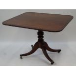 A George IV mahogany tilt top rectangular table with turned baluster pedestal with four splayed