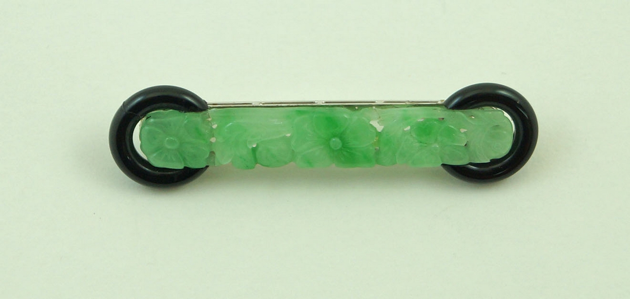 A carved jade and black onyx panel brooch,