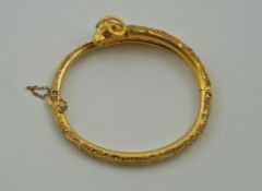 An archaeological revival gold hinged bangle, with a rams head terminal,