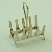 A small silver toast rack with four open divisions and a central loop handle on out swept bracket