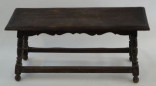 An oak and beech stool with turned legs linked by rectangular stretchers, 47cm high, 94cm wide,