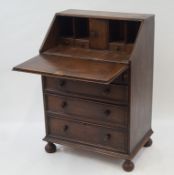 An oak bureau with fall front above a carved drawer and three further drawers,