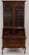 A mid 20th century bureau bookcase with two glazed doors above a fall front and three graduated