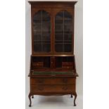 A mid 20th century bureau bookcase with two glazed doors above a fall front and three graduated