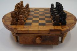 A walnut and ebonised chessboard above two drawers containing a carved chess set on turned legs, 35.