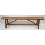 A French fruitwood bench with trestle style feet linked by a stretcher,