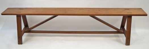 A French fruitwood bench with trestle style feet linked by a stretcher,