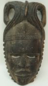 A carved ebony tribal mask with elaborate pierced headdress, 43cm high,