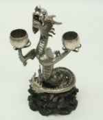 A Chinese silver figure of a dragon holding two bowls, by Hung Chong, on a carved wooden stand, 22.