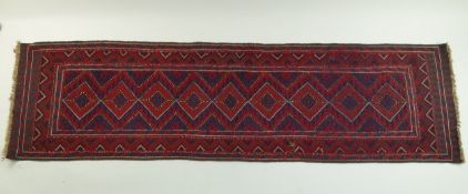 A decorative runner with diamond shaped lozenges in red and blue on a geometric zig zag field