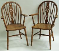 A pair of Windsor elbow chairs with ash seats on turned legs linked by H stretchers