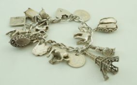 A white metal charm bracelet, stamped silver, with various charms, 76.