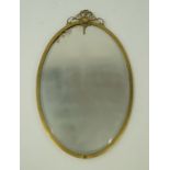 An oval brass framed wall mirror with rosette and scrollwork crest, overall 84cm high,