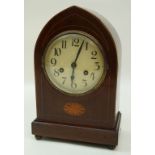 An early 20th century mahogany lancet shaped mantel clock with oval patera, standing on ball feet,