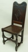 An 18th century oak panelled chair with carved back and solid seat,