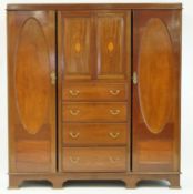 An Edwardian mahogany triple wardrobe with two marquetry cupboard doors above four drawers flanked