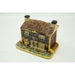 A Victorian majolica cottage biscuit barrel, the roof opening to reveal a turquoise glazed interior,