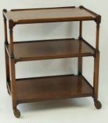 A mahogany three tier trolley on turned and rectangular supports on rubber wheels, 76.
