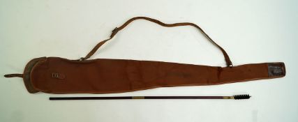 A vintage brown canvas gun slip and a wooden and brass two piece gun cleaning rod