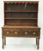 An oak dresser with raised plate rack above two deep drawers with split turned mouldings,