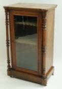 A Victorian walnut standing display cabinet with turned columns flanking a glazed door enclosing