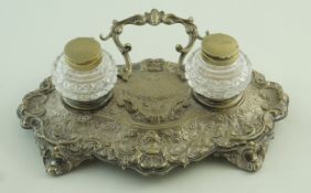 A 19th century plated inkstand, in the rococo taste, the two glass wells to the shaped base,