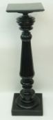 An ebonised torchere with square top and reeded and turned baluster pedestal on plinth base, 26.