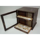 An early 20th century mahogany specimen cabinet containing a large collection of microscopic slides