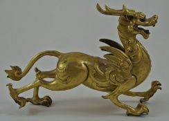 A Chinese gilded bronze figure of a dragon cast with horns, wings and legs out stretched,