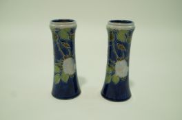 A pair of Royal Doulton stoneware vases each with tubelined roses on a blue ground,