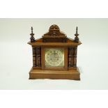 An early 20th century oak cased mantel clock with an Enfield movement, turned finials,