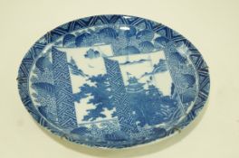 A Japanese porcelain charger printed in blue with landscapes on a leaf and flower ground,