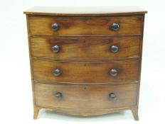 A mahogany bow fronted chest of four graduated drawers with turned handles on splayed feet,