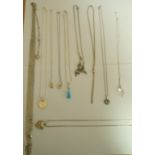 A collection of ten silver or silver coloured pendants on chains