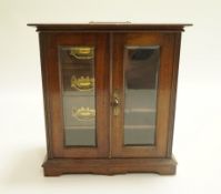 An early 20th century mahogany smoker's cabinet with three fitted drawers and pipe hanging rack.