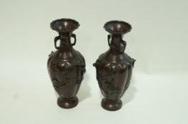 A pair of two handled Japanese bronze patinated vases of lobed form with birds on branches in