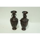 A pair of two handled Japanese bronze patinated vases of lobed form with birds on branches in