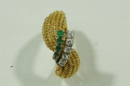 A diamond and emerald dress ring, tagged '750',