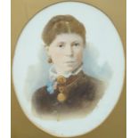 A Victorian tinted photograph on a ceramic base in oval frame surmounted by a ribbon,