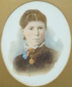 A Victorian tinted photograph on a ceramic base in oval frame surmounted by a ribbon,